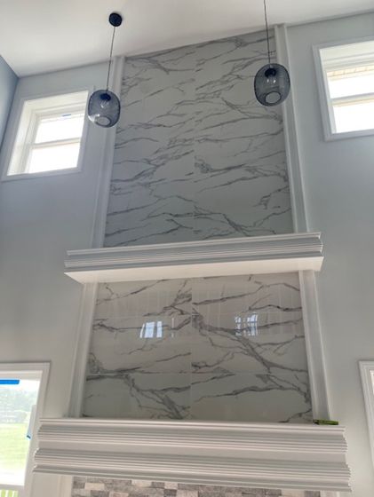 A room with a marble wall and two lights hanging from the ceiling