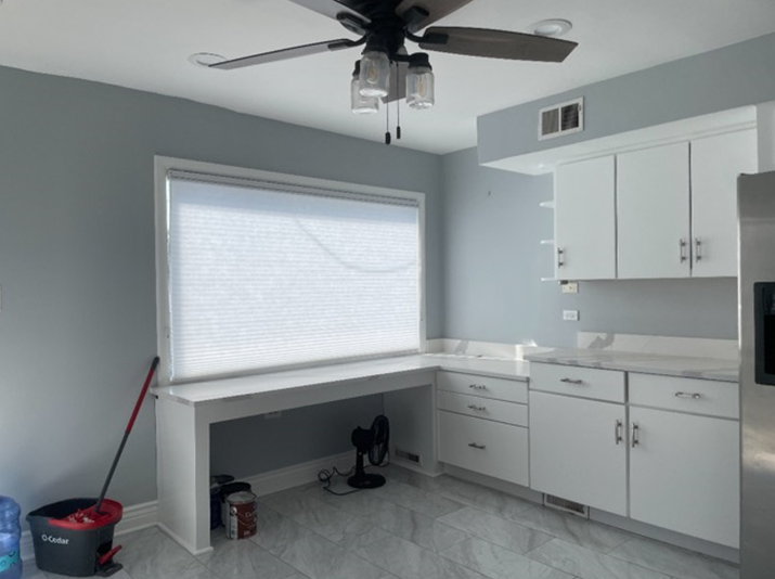 A kitchen with white cabinets and a ceiling fan