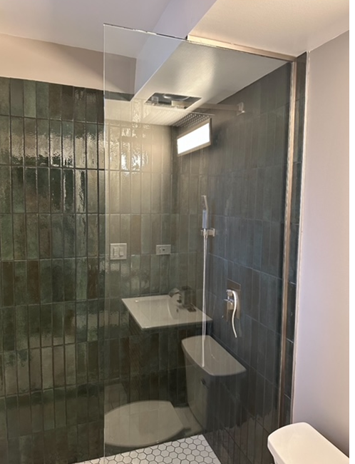 a bathroom with a toilet , sink and shower with a glass door .