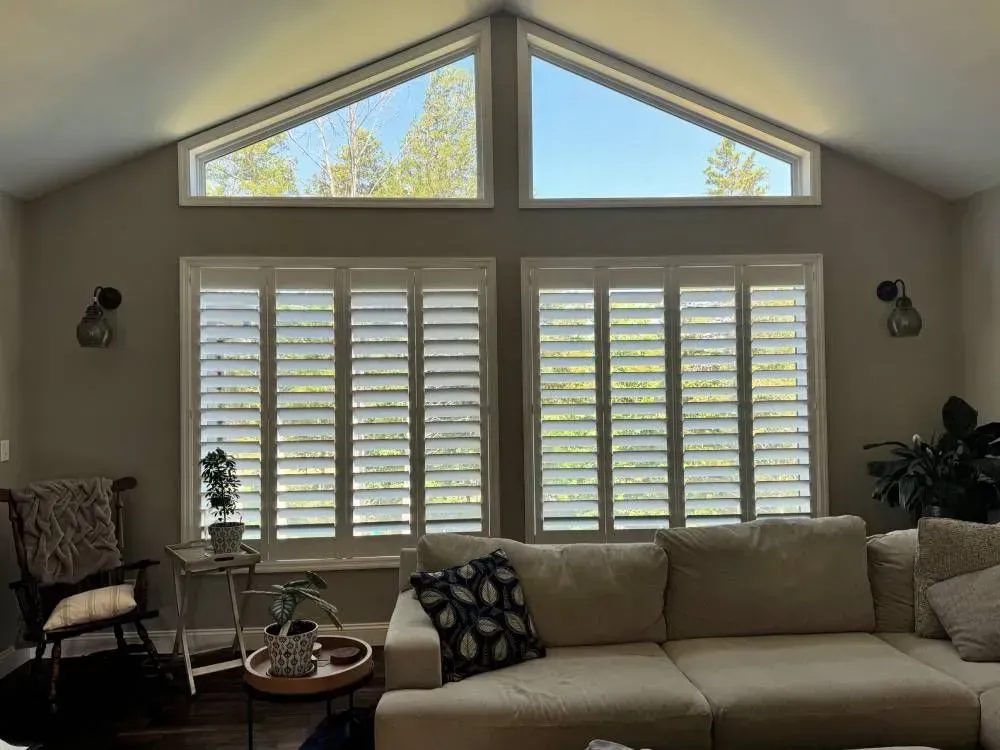 Living room with beige walls, white shutters, and a large sectional sofa.