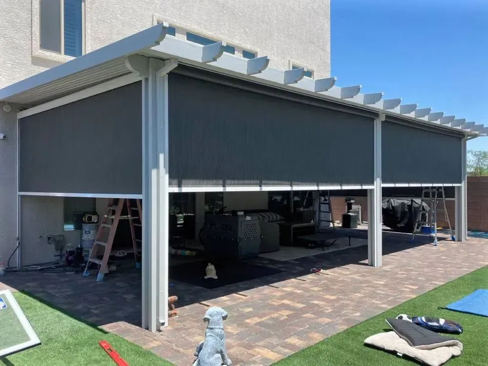 Patio with retractable gray shades, white frame, and brick flooring.