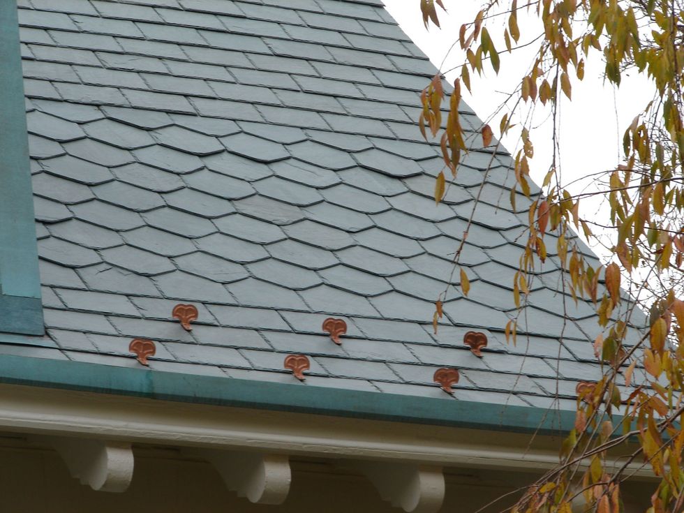 Slate roof with scalloped shingles, autumn leaves, and a green gutter under the eaves