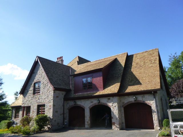 Stone house with gabled roof, arched garage doors, and blue sky overhead