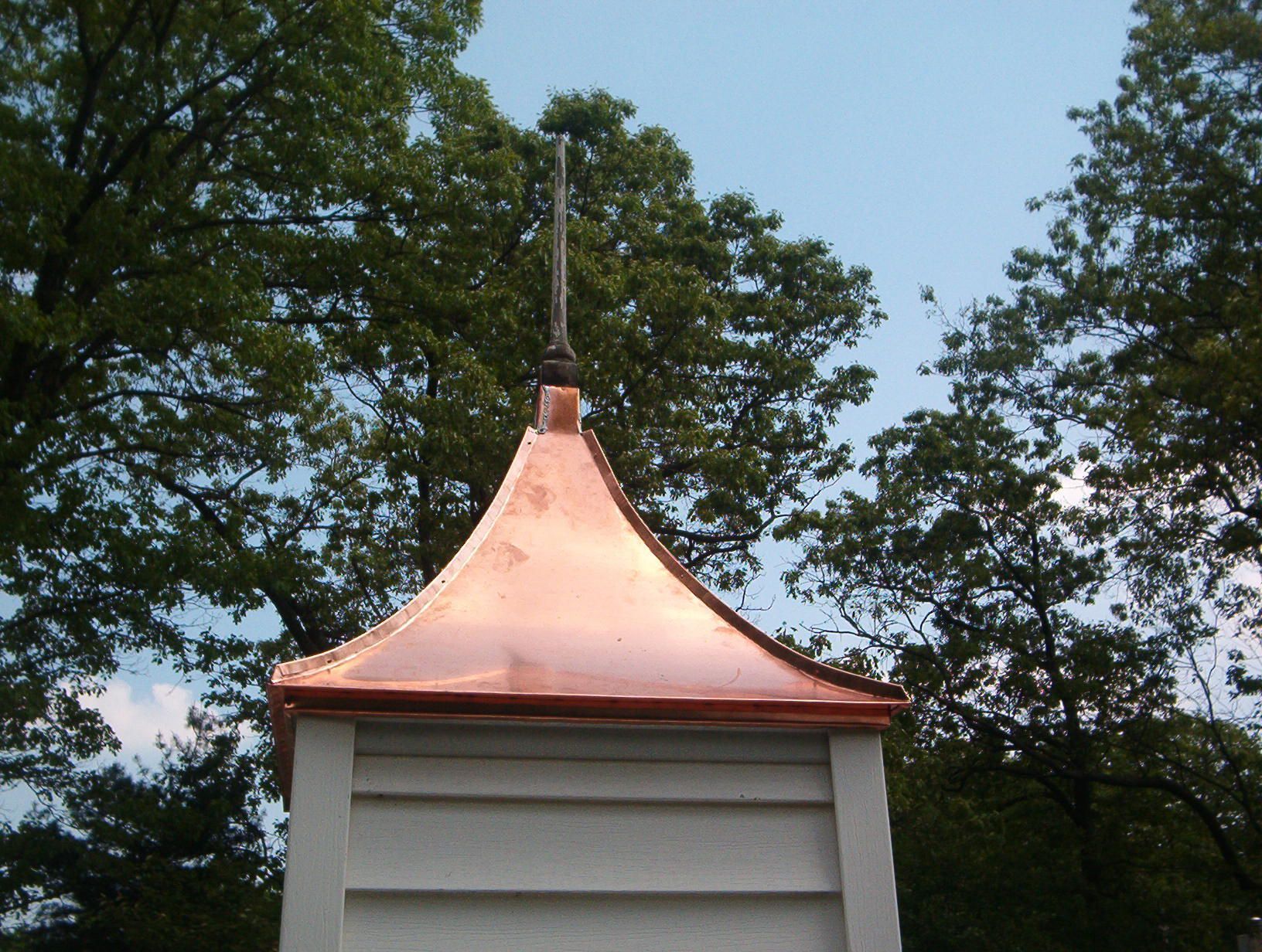Copper roofed tower against trees and sky