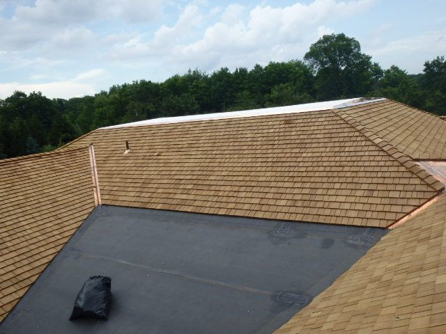 Roof under construction with tan shingles and a black waterproofing membrane section