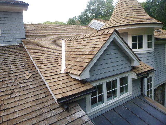 Blue house roof with tan shingles, dormer windows, and a small conical turret