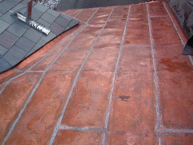 Red tiled roof with gray shingles and skylight in the upper left corner