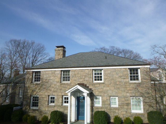Stone house with blue front door, white trim, and chimney under a clear sky