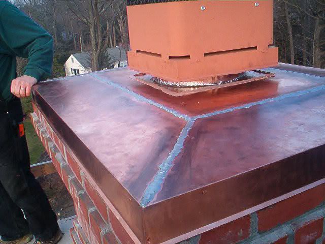 Person standing beside a rust-colored rooftop vent on a metal roof, with steam or smoke rising nearby