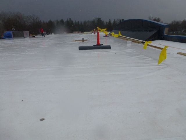 Snowy ski slope with orange markers and yellow flags under an overcast sky