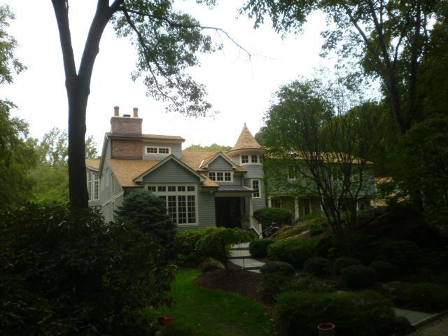 Large house with a green roof and garden path surrounded by trees