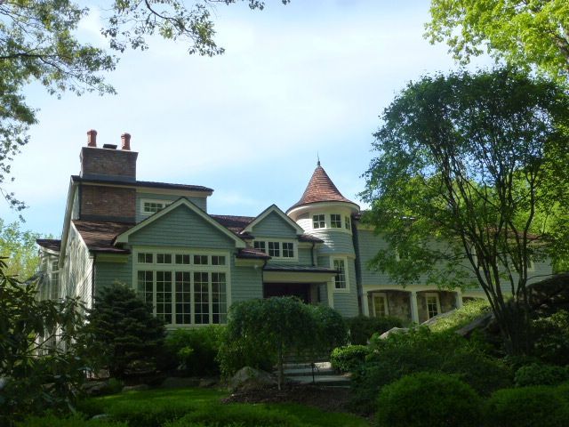 Large green house with a turret, surrounded by trees and lush garden greenery