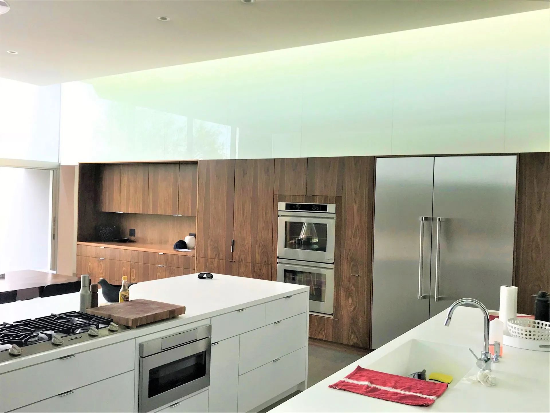 Modern kitchen with white island, stainless steel appliances, and wood-accented cabinetry