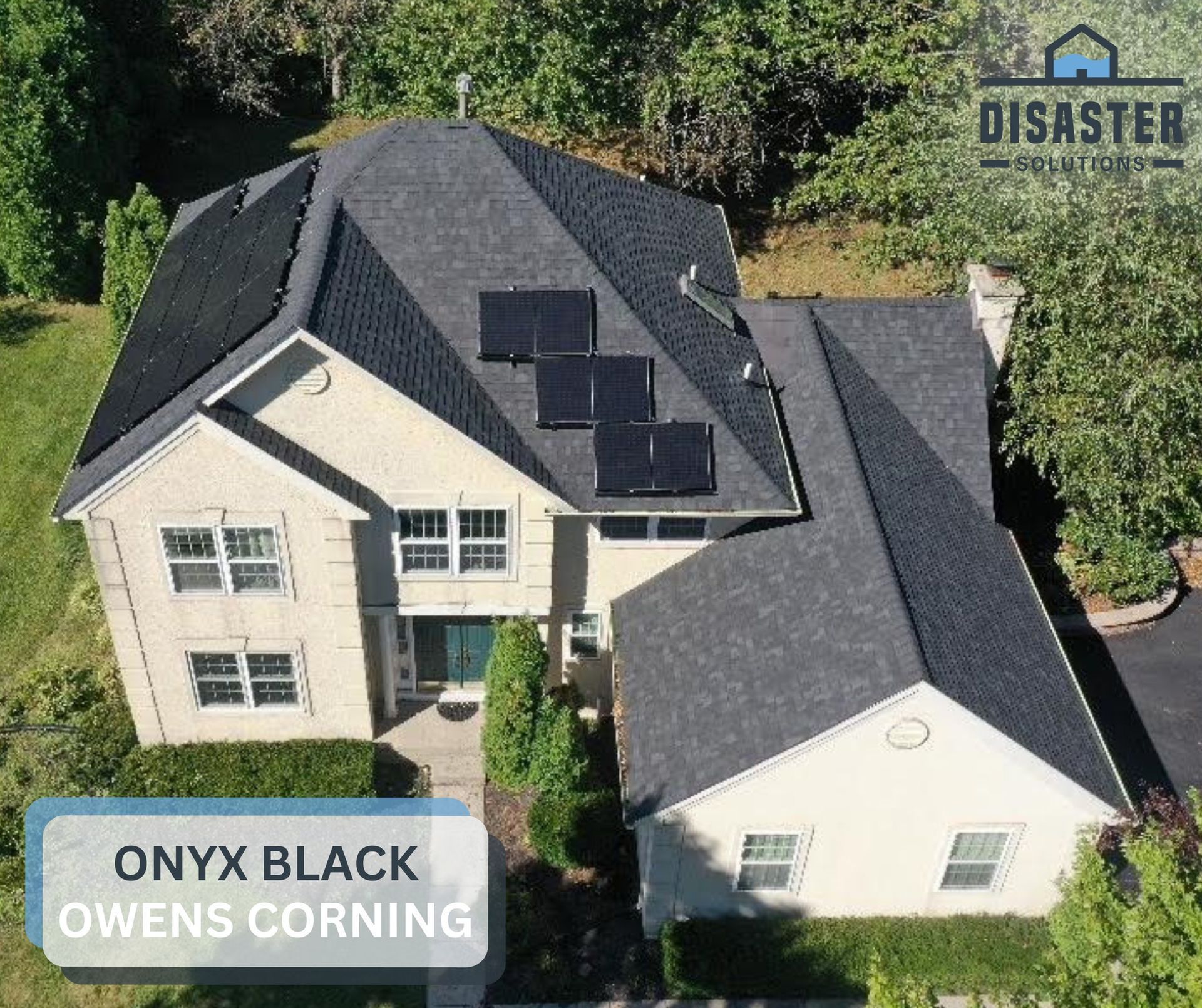 Overhead view of a two-story house with black roofing and solar panels, surrounded by trees.