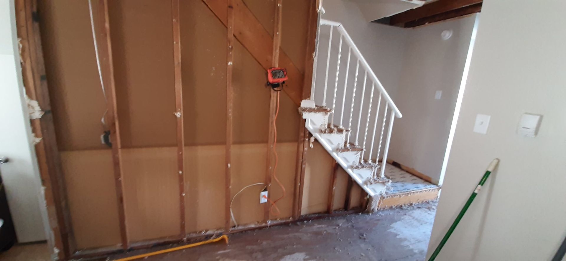 Two roofers working on a roof, installing shingles. One kneels, the other stands, using a tool.