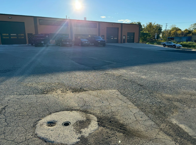 Parking lot outside a brick building with garage doors, seen in bright sunlight