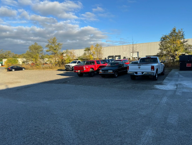 Parking lot with several pickup trucks under a partly cloudy sky near a beige building
