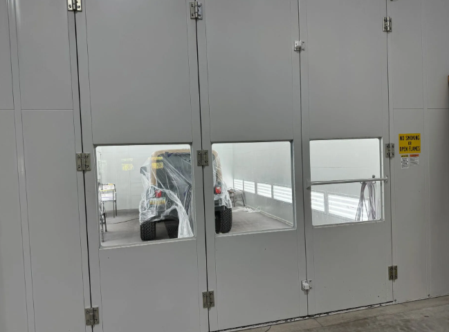 Gray industrial doors with small windows revealing a covered vehicle inside a garage.