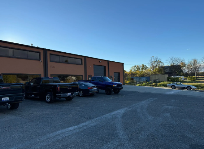 Parking lot beside a tan building with parked cars under a clear blue sky