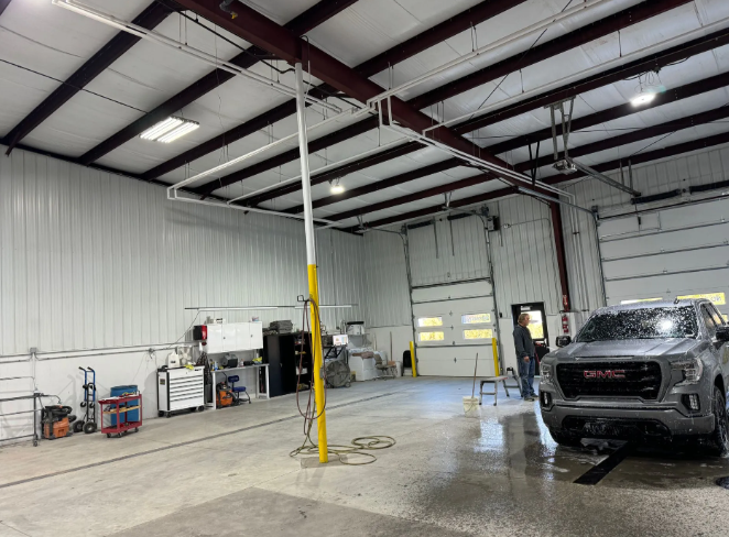 Large industrial garage with a white service bay and a gray GMC truck parked inside.