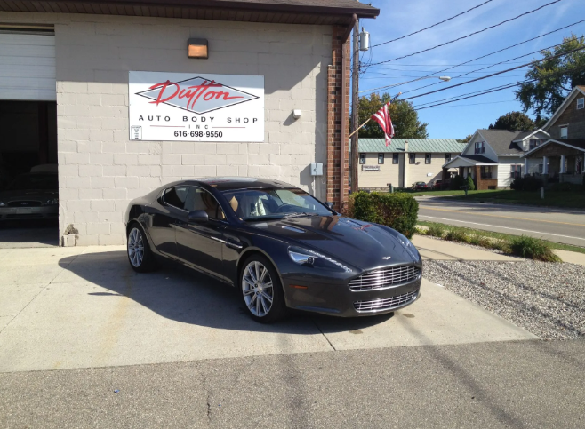 Black sports car parked outside a brick auto shop on a sunny day