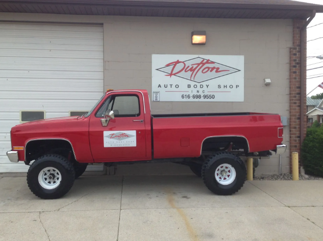 Red pickup truck parked outside Dutton Auto Body Shop