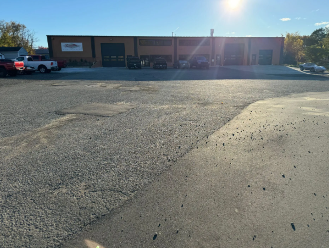 Sunny parking lot in front of a low brick commercial building with parked cars