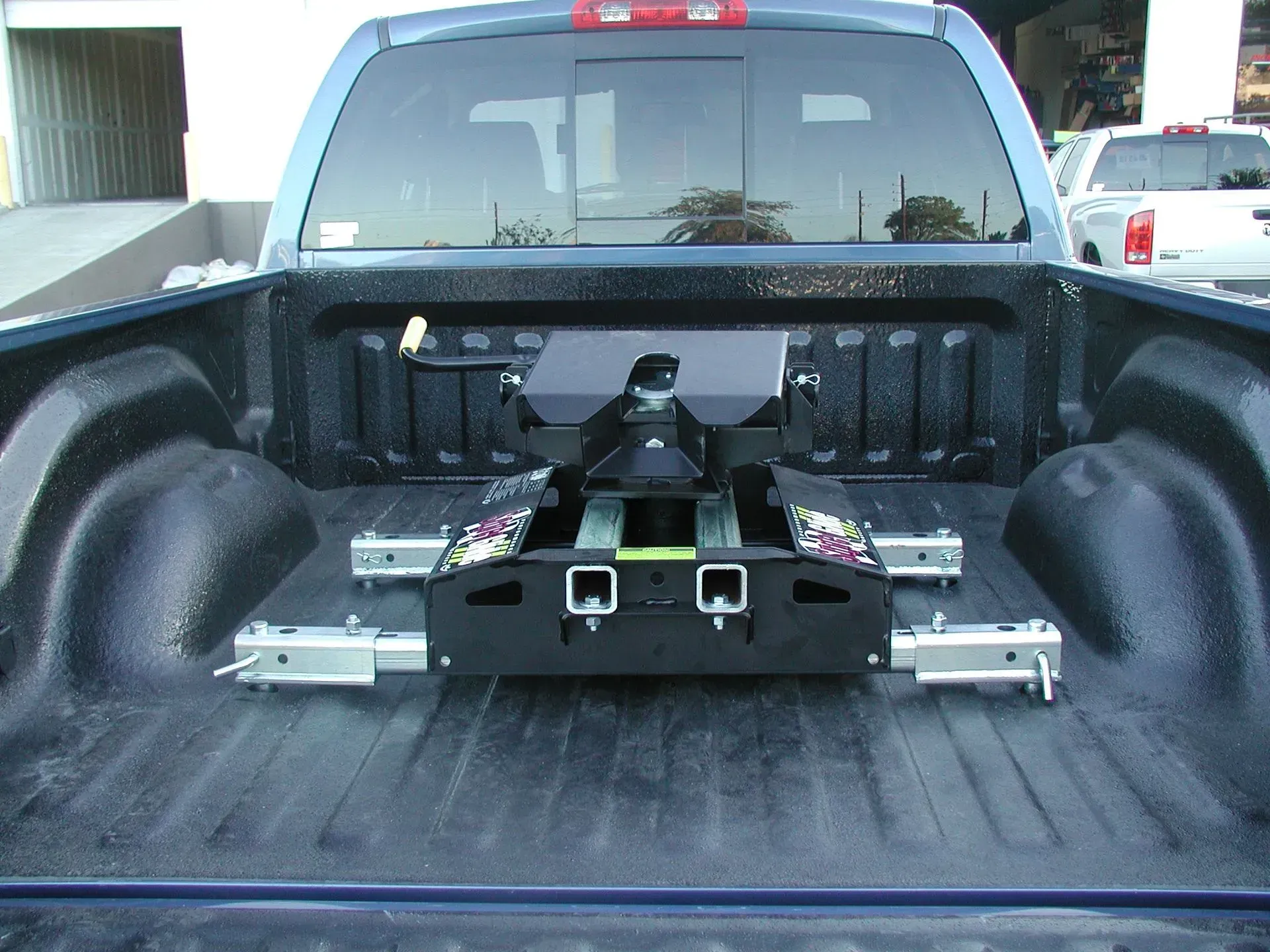 A fifth-wheel hitch installed in the bed of a blue pickup truck.