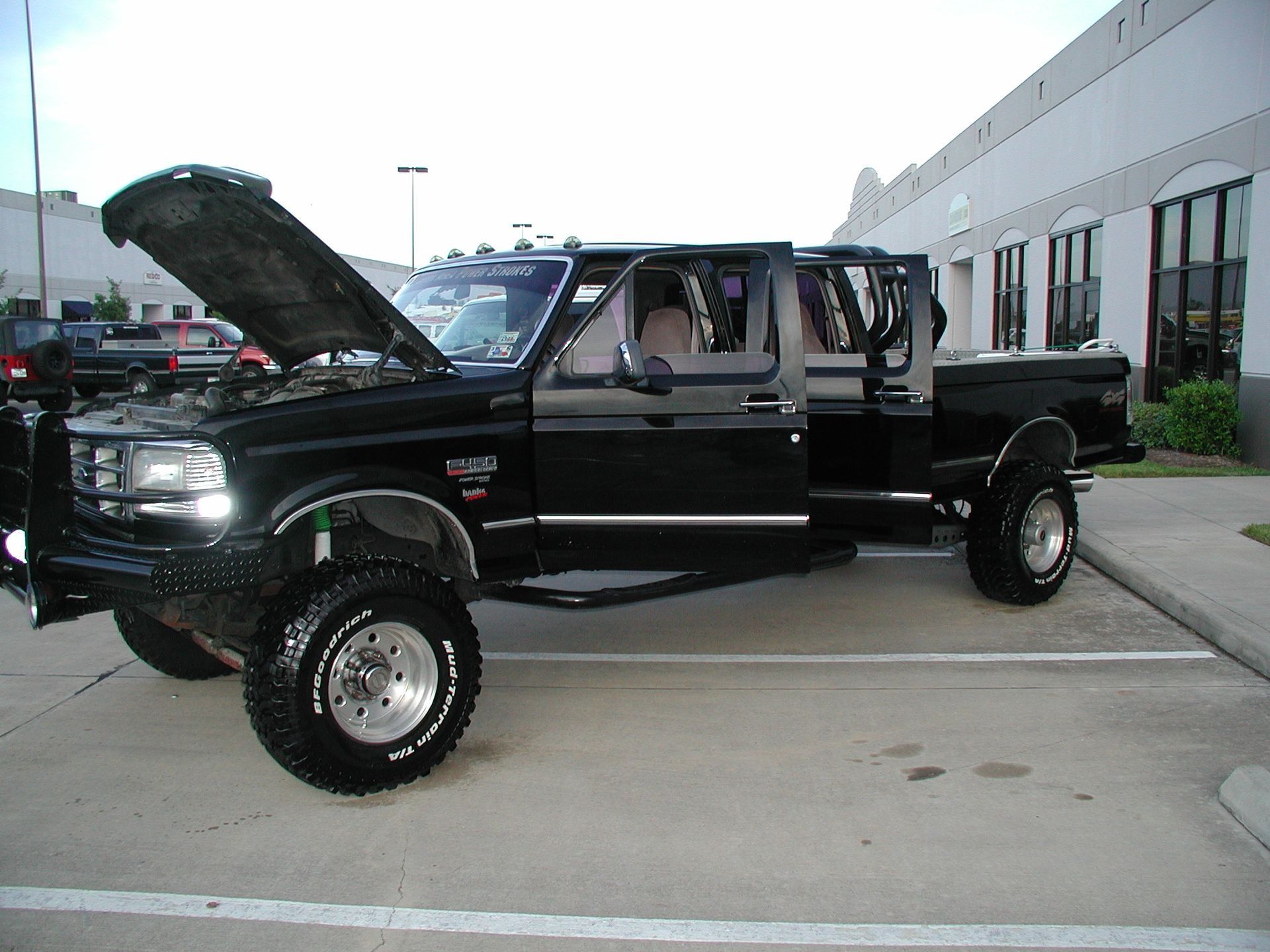 Black extended cab pickup truck, hood open, parked in a lot.
