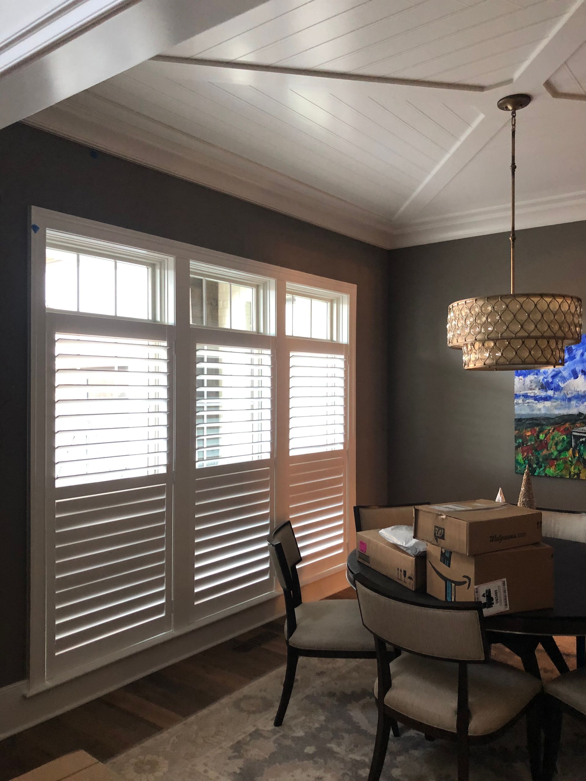 Interior view of a dining room with white shutters, dark gray walls, and a decorative ceiling.