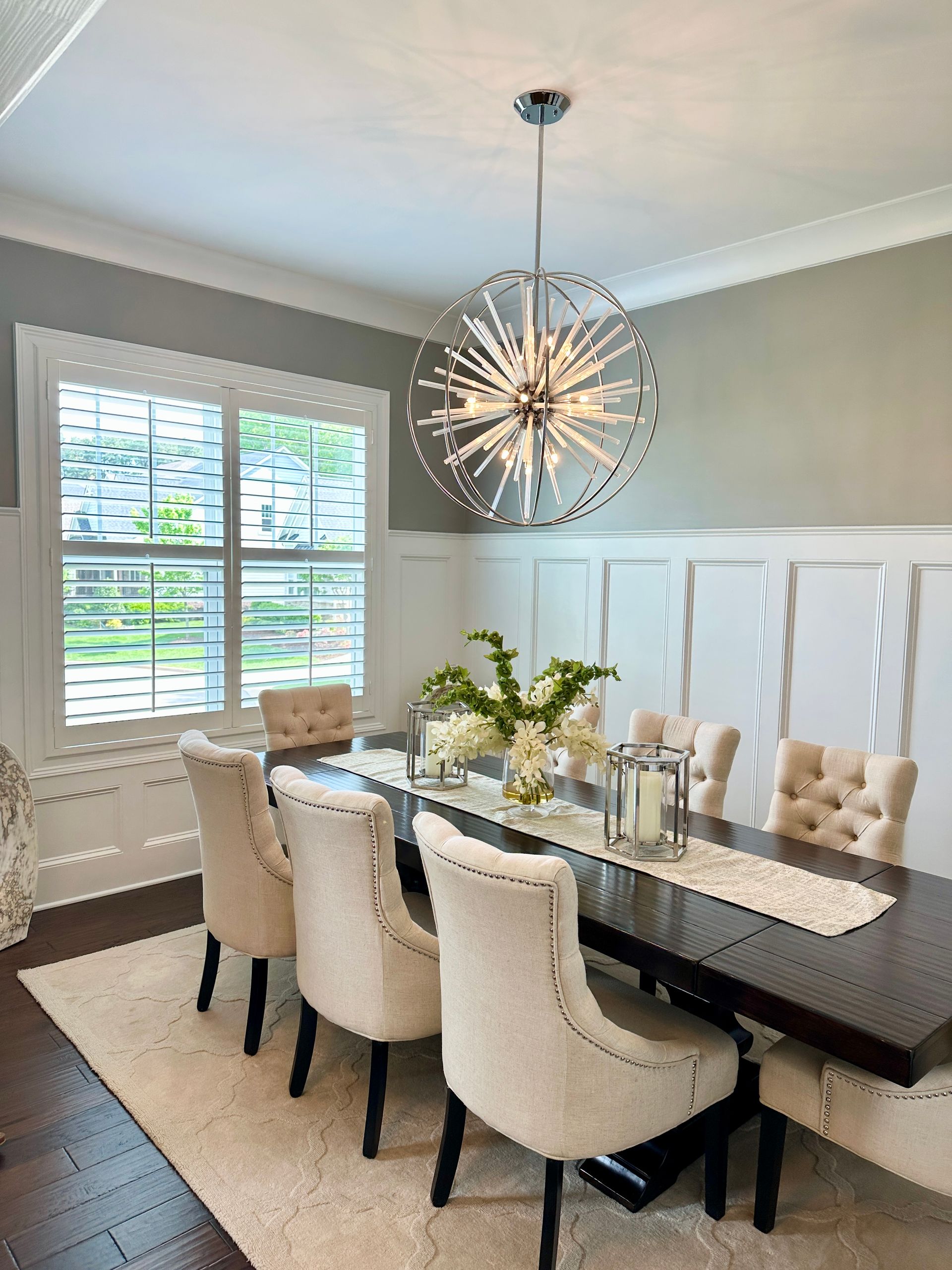 Formal dining room with dark table, upholstered chairs, and a starburst chandelier.