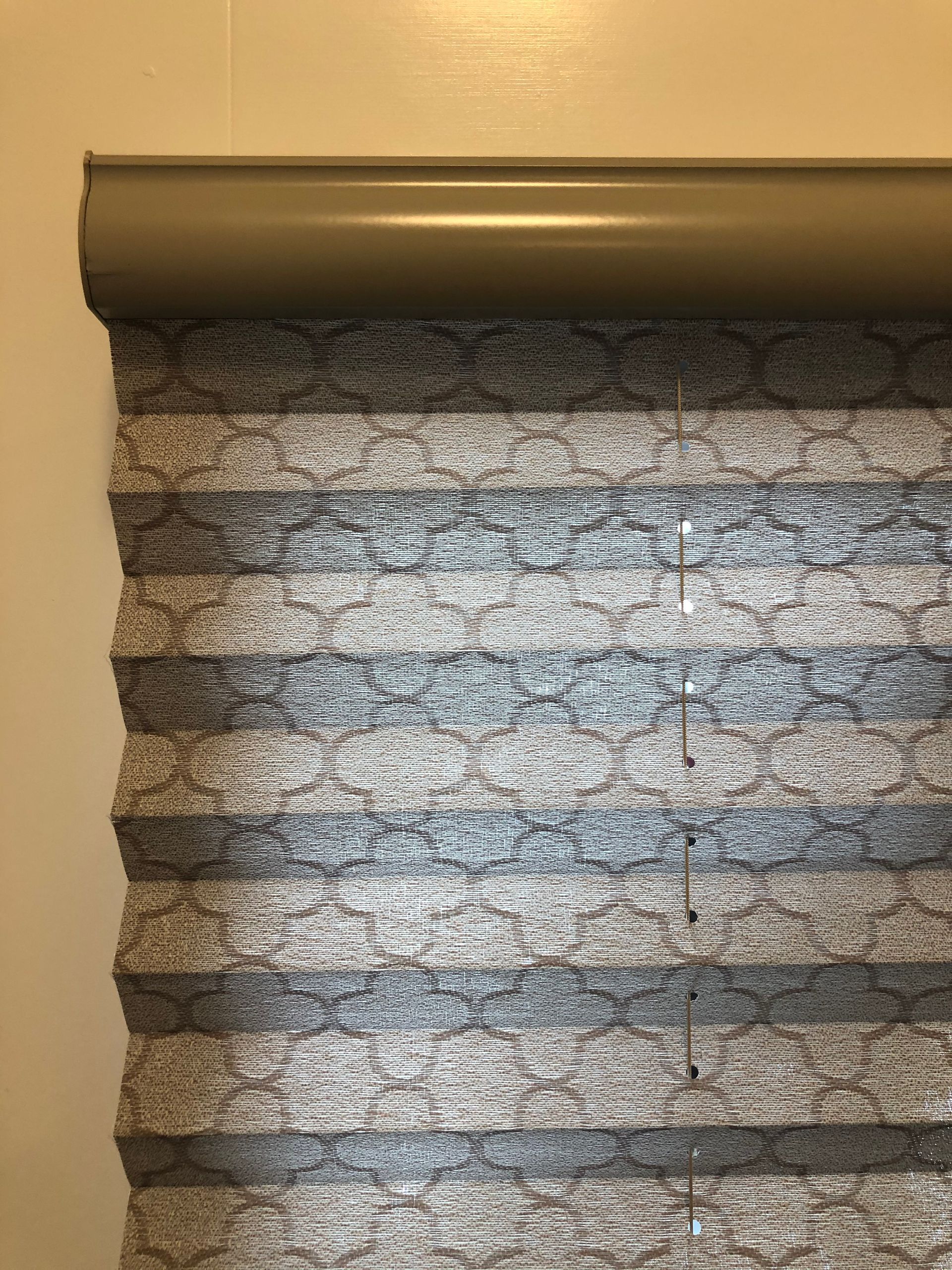 Gray and blue cellular shades partially drawn, top section visible against a light-colored wall.