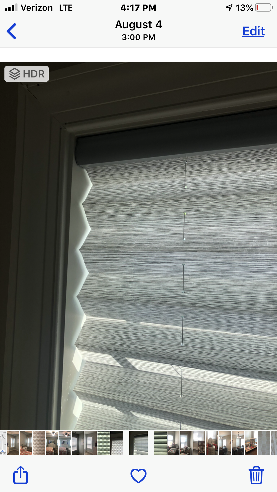 Close-up of a window with light gray honeycomb blinds, partially drawn down.