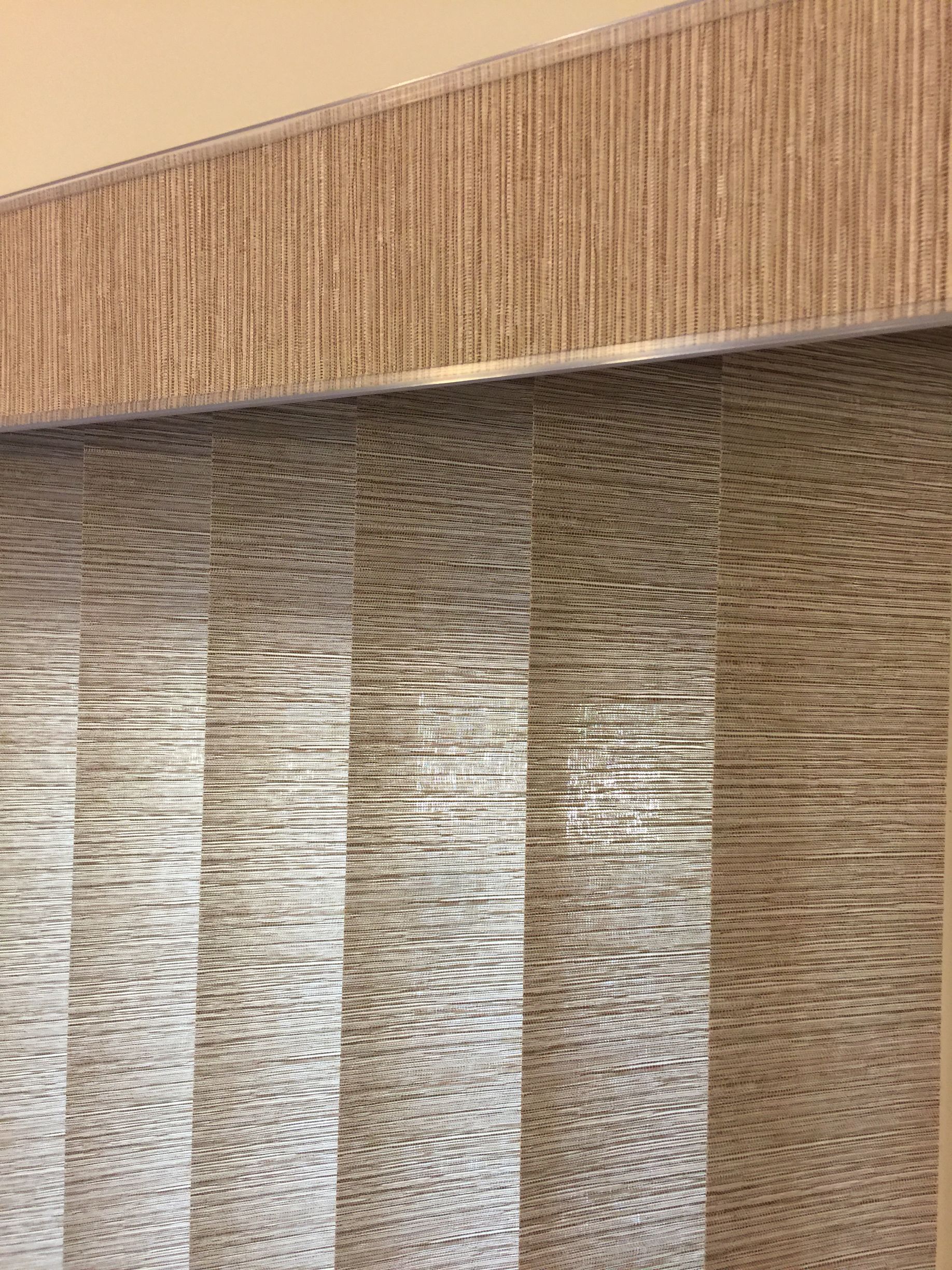 Vertical blinds with a matching valance in shades of brown and beige.