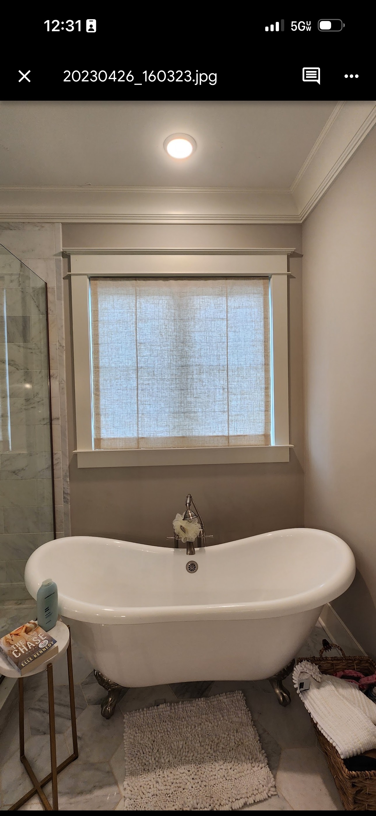 Bathroom with a claw-foot tub under a window with a woven shade.