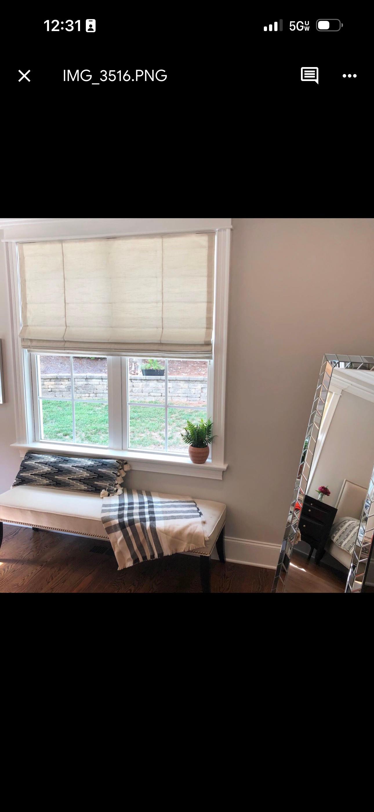 Window seat with a bench, pillows, and a blanket. A mirror sits in the corner.