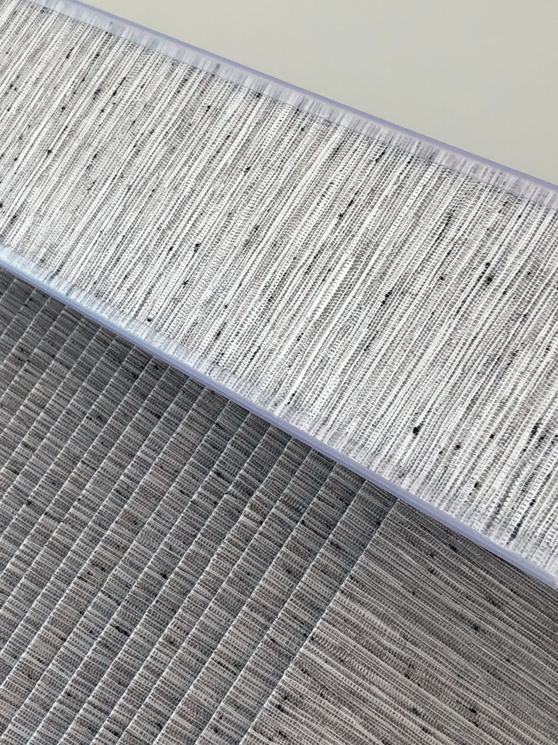 Close-up of a woven gray textile with a white border, possibly a rug or fabric sample.