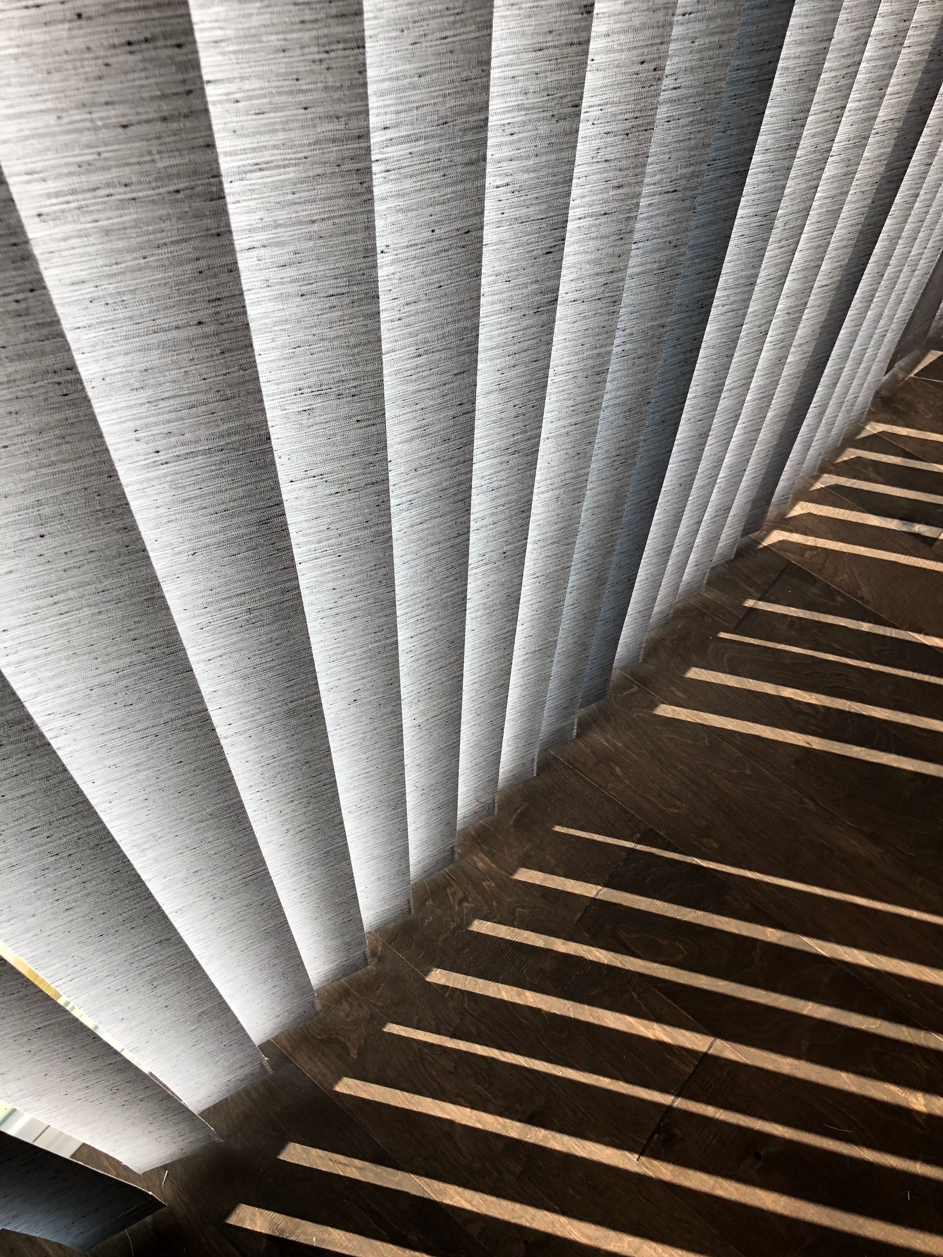 Staircase with light filtering through blinds, creating alternating bands of light and shadow.