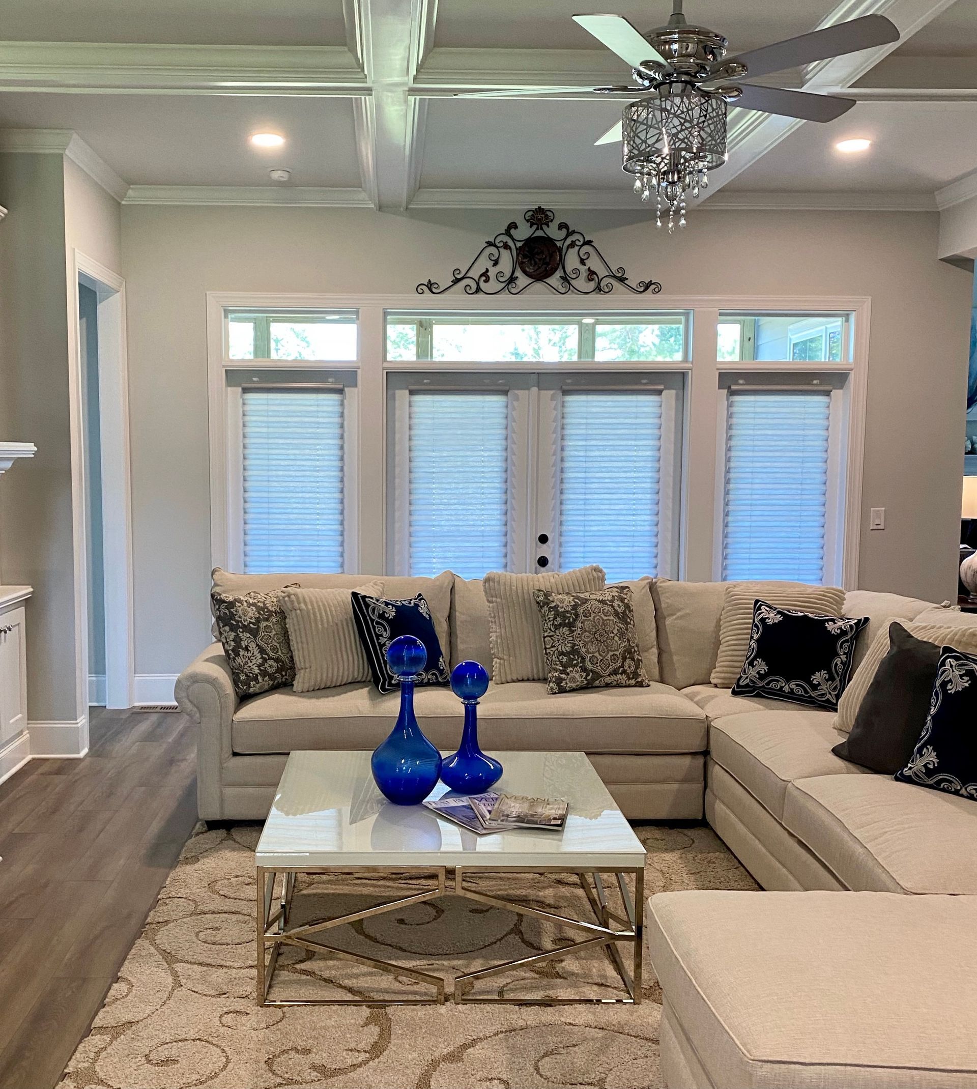 Living room with cream sectional sofa, marble coffee table, and large window with blinds.