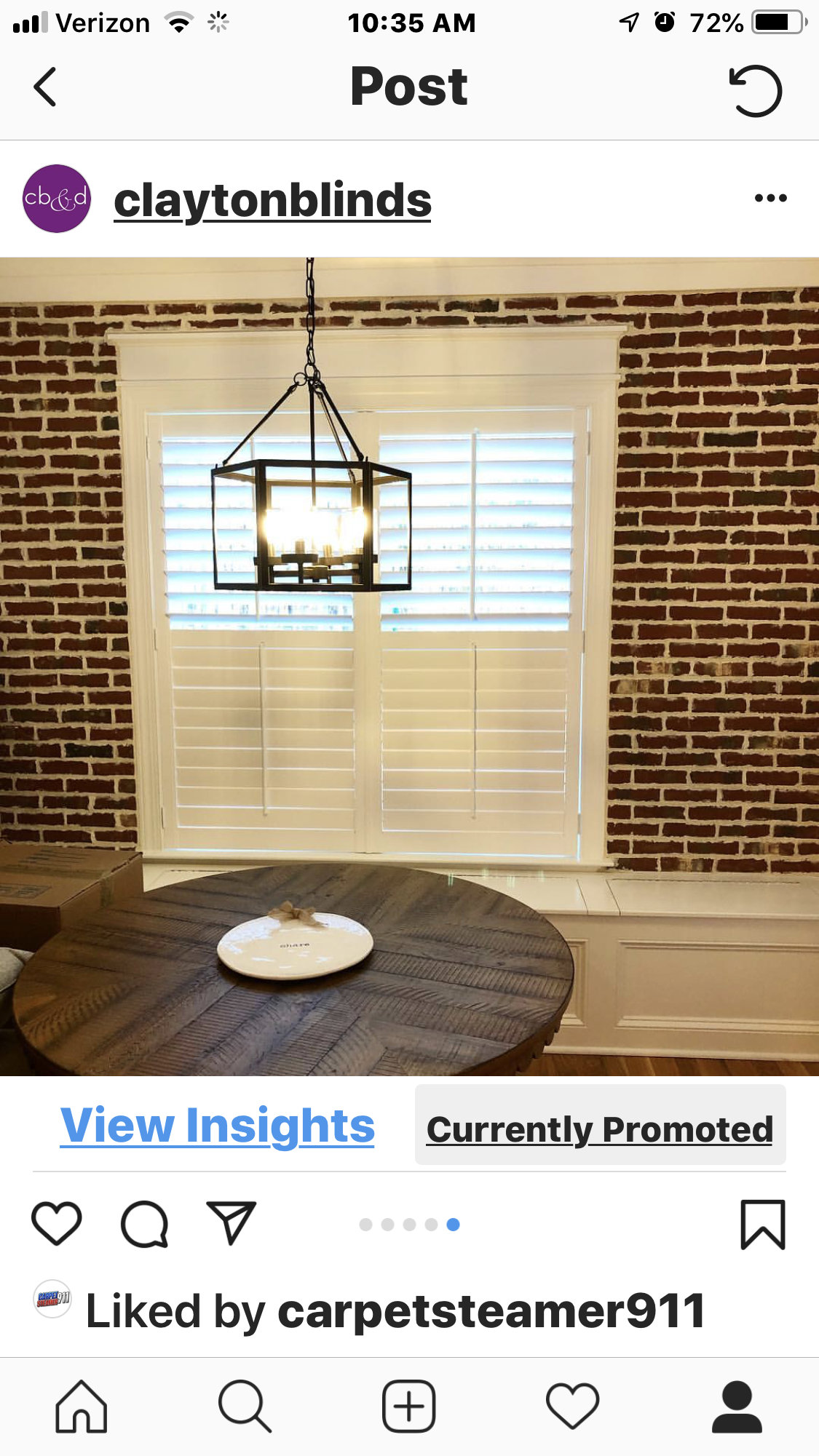 Dining room with wooden table, shutters, brick wall, and hanging light fixture.