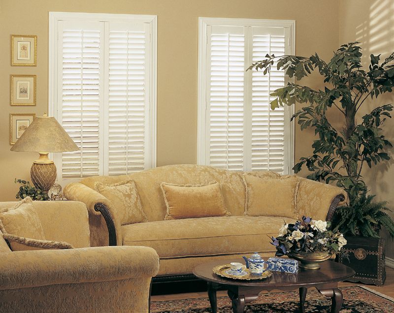 Living room with beige sofa, shutters, lamp, and coffee table.