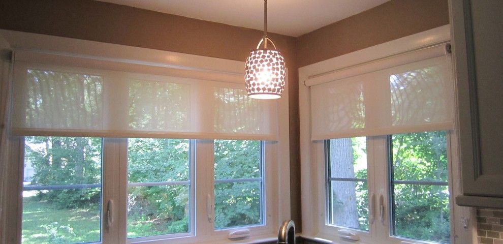 Kitchen corner with windows, light-colored shades, and a pendant light fixture. Brown wall and white trim.