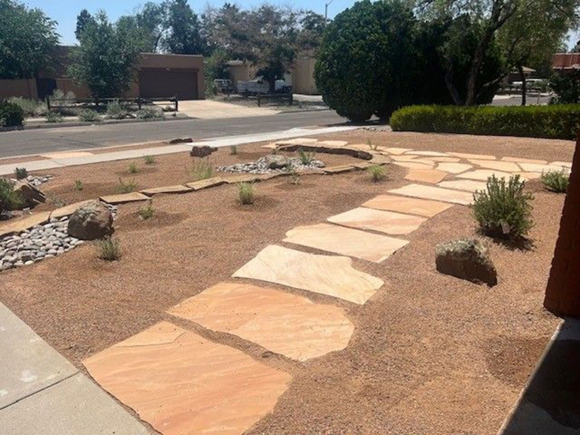 A stone walkway leads to a house in a residential area.
