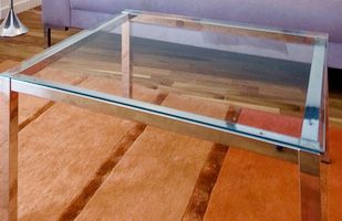 A glass coffee table is sitting on a rug next to a couch
