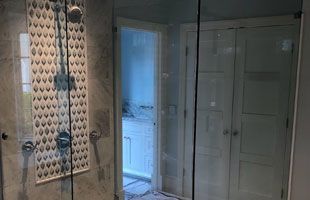A bathroom with a walk-in shower and a glass door
