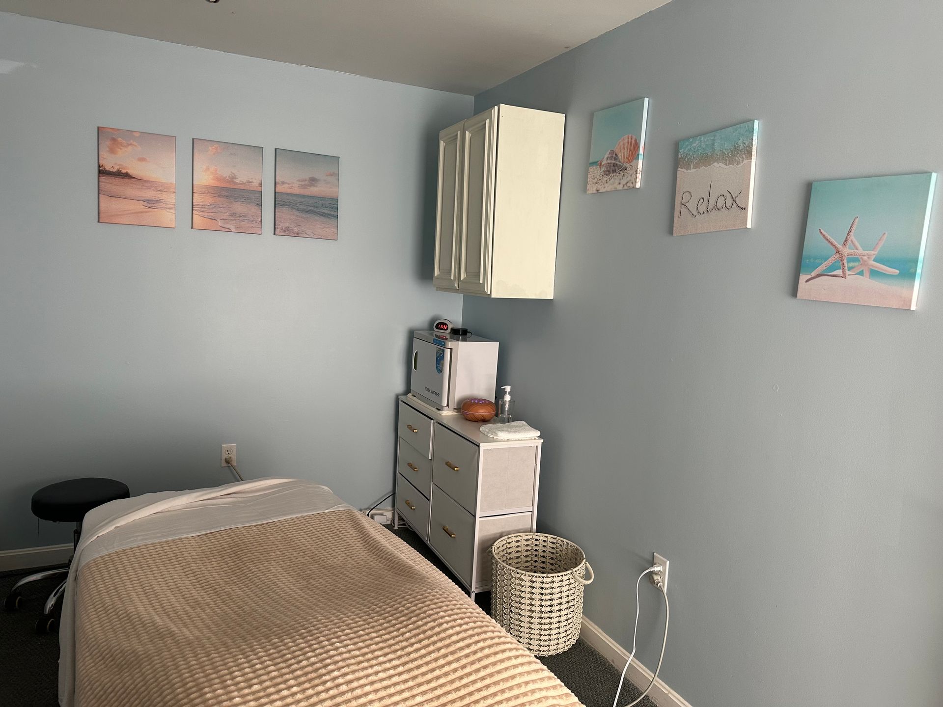 Massage therapy room with light blue walls, art, and a massage table.
