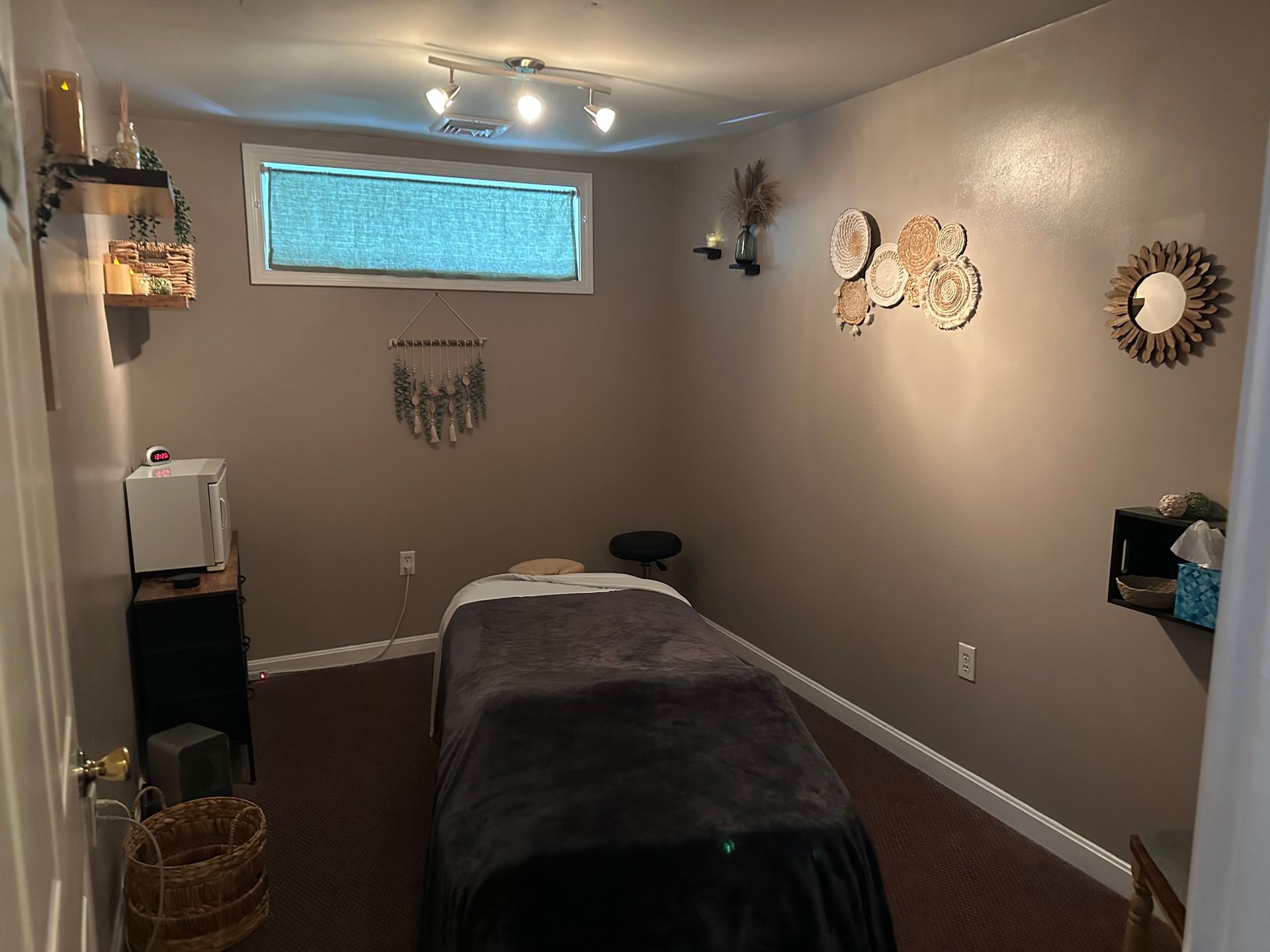 Massage therapy room with massage table, neutral walls, decorative items.