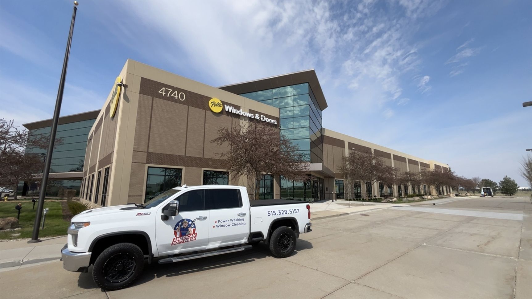 White pickup truck parked outside a modern commercial building on a sunny day