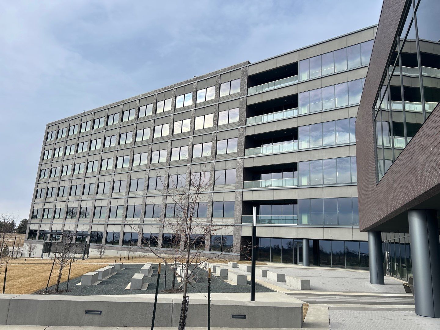 Modern office building with glass windows and dark brick exterior on a landscaped urban street