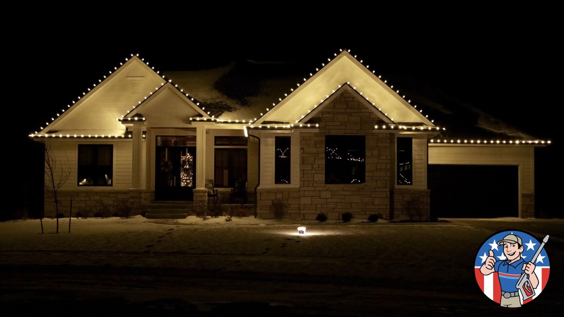 Single-story house at night, outlined with warm string lights and a lit garage.